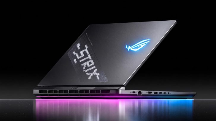 An ASUS ROG laptop with a glowing blue logo on the lid, illuminated with pink and blue light, and the word 'STRIX' displayed on its customizable rear panel.