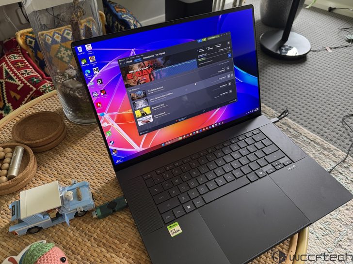 A laptop with an 'NVIDIA GeForce RTX' sticker shows the Steam application with the game 'Cyberpunk 2077' on the screen.