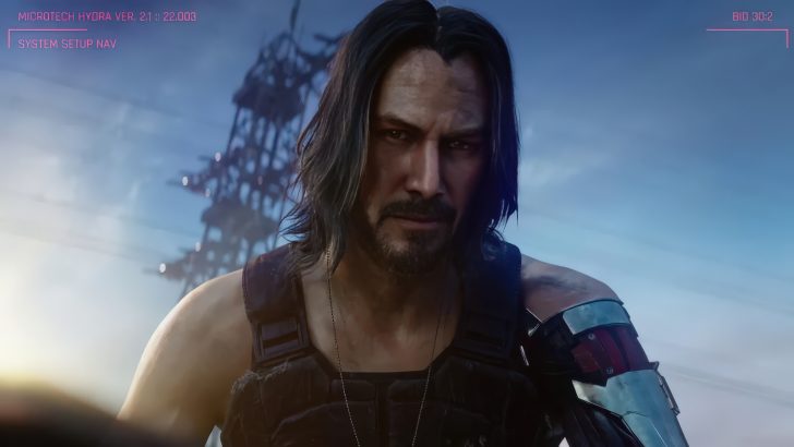 Johnny Silverhand (played by Keanu Reeves) from the game 'Cyberpunk 2077' with a cybernetic arm stands against a backdrop of a futuristic cityscape with on-screen text 'Microtech Hydra ver. 2.1 :: 22.003' and 'System Setup Nav'.
