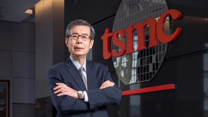 An executive stands in a professional setting with a prominent tsmc logo in the background.