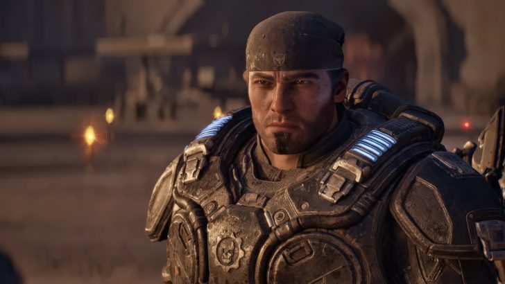 Marcus Fenix in 'Gears of War: E-Day' wearing futuristic armor with glowing blue lights stands in a desert battle setting.